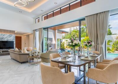 Modern living room with large windows, elegant dining area, and view of outdoor garden and pool