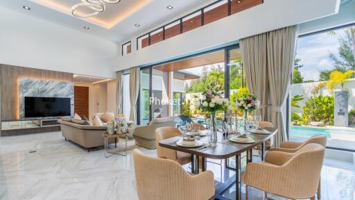 Modern living room with large windows, elegant dining area, and view of outdoor garden and pool