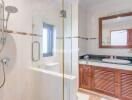 Bathroom featuring glass shower enclosure, sink with large mirror, and wooden vanity