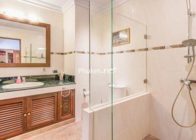 Spacious bathroom with a wooden vanity, large mirror, and a glass-enclosed shower area