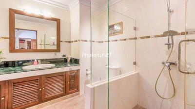 Spacious bathroom with a wooden vanity, large mirror, and a glass-enclosed shower area