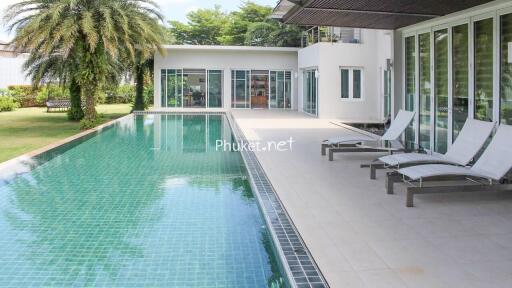 Luxurious outdoor pool area with modern loungers and lush greenery