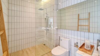 Modern bathroom with glass shower, tiled walls, and wooden accents