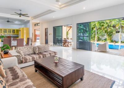 Spacious living area with modern decor, adjacent kitchen and pool view
