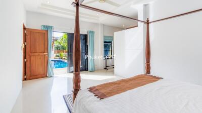 Bedroom with a canopy bed and view of the pool through glass doors