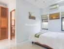 Spacious bedroom with attached bathroom, wardrobe, and air conditioning