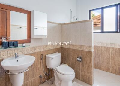 Modern bathroom with sink, toilet, mirror, and wall tiles