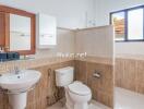 Modern bathroom with sink, toilet, mirror, and wall tiles