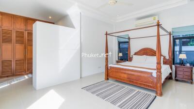 Spacious bedroom with wooden four-poster bed and wardrobe