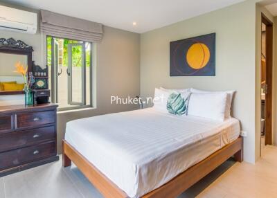 Bedroom with window, wooden bed, and dresser