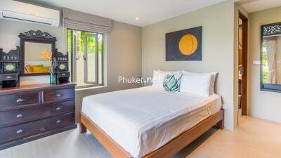 Bedroom with window, wooden bed, and dresser