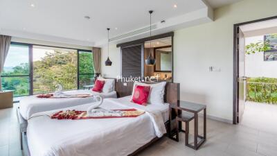 Modern bedroom with two single beds, large windows, and a scenic view.