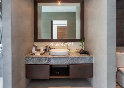 Modern bathroom with a large mirror, sink, and toiletries