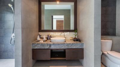 Modern bathroom with a large mirror, sink, and toiletries