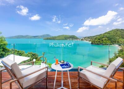 Stunning balcony view of the ocean and surrounding hills with cozy seating.