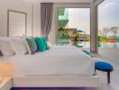 Modern bedroom with ocean view, large bed, colorful pillows, and glass sliding doors leading to a pool area