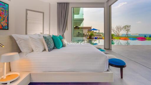 Modern bedroom with ocean view, large bed, colorful pillows, and glass sliding doors leading to a pool area