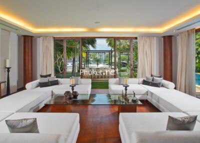 Spacious living room with white sofas, large glass table, and pool view.