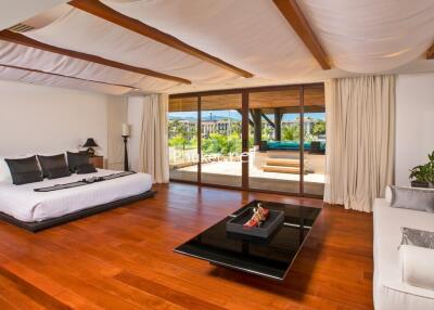 Spacious bedroom with wooden flooring and large windows opening to a balcony