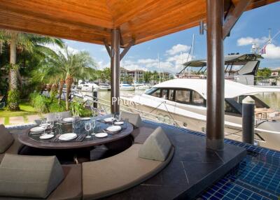 Outdoor patio with a circular dining table and view of boats docked at a marina