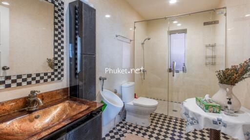 Modern bathroom with glass shower, toilet, sink, and decorative elements