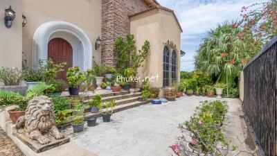 Front entrance of a house with a stone path, potted plants, and a lion statue