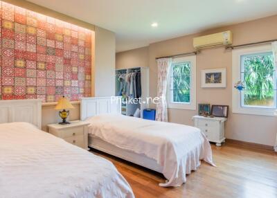 Spacious bedroom with two single beds and decorative tile accent wall