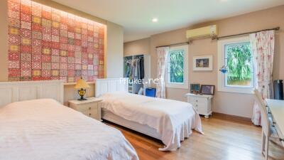 Spacious bedroom with two single beds and decorative tile accent wall