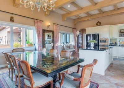 Elegant dining room with a large glass table and kitchen in the background