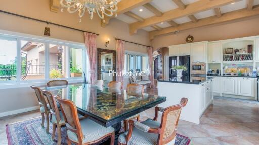 Elegant dining room with a large glass table and kitchen in the background