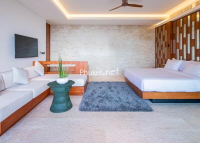 Modern bedroom with a large bed, sofa, wall-mounted TV, and decorative elements