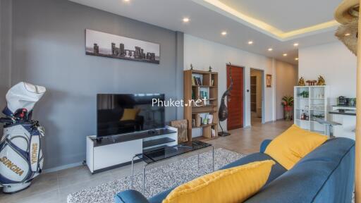 Modern living room with a TV, bookshelf, and golf bag