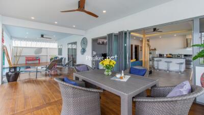 Modern open-plan living area with dining table, kitchen, and poolside seating