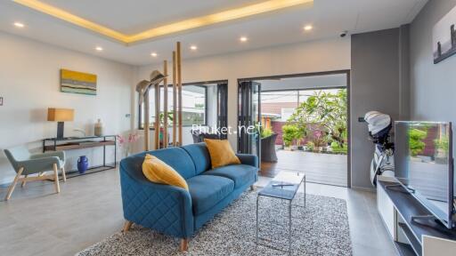 Modern living room with blue sofa and large glass doors opening to garden