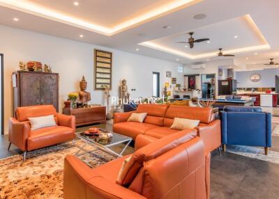 spacious and modern living room with leather sofas, decorative items, and kitchen in the background