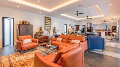 spacious and modern living room with leather sofas, decorative items, and kitchen in the background