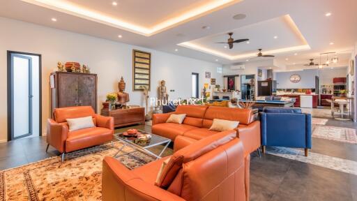 spacious and modern living room with leather sofas, decorative items, and kitchen in the background