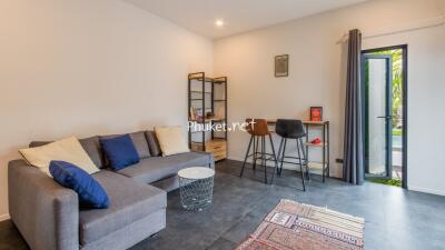 Living room with sofa, coffee table, bar stools, and access to outdoor area.