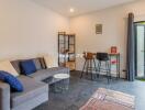 Living room with sofa, coffee table, bar stools, and access to outdoor area.