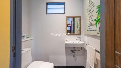 Small bathroom with toilet, sink, mirror, and wall art