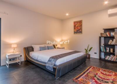 Spacious modern bedroom with double bed, bookshelf, and artwork