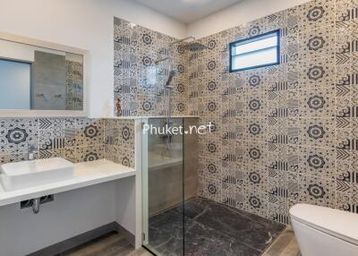 Modern bathroom with patterned tiles, glass-enclosed shower, and sleek fixtures