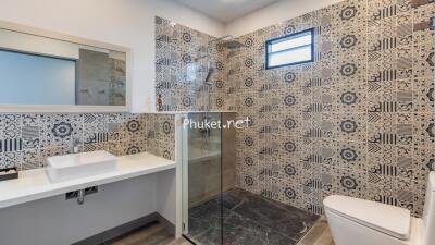 Modern bathroom with patterned tiles, glass-enclosed shower, and sleek fixtures