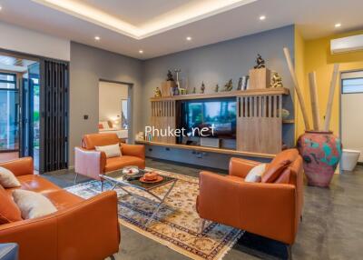Modern living room with orange leather sofas, wall-mounted TV and decorative shelving