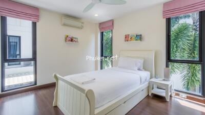 Bright bedroom with white bed, pink curtains, and large windows