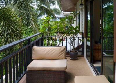 A balcony with outdoor seating overlooking tropical greenery