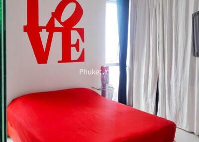 Bedroom with red bedspread and wall decor
