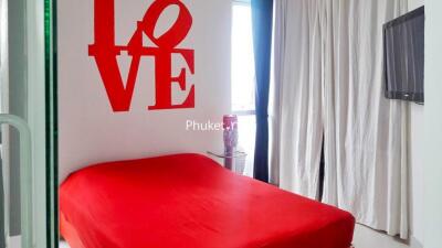 Bedroom with red bedspread and wall decor