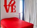 Bedroom with red bedspread and wall decor