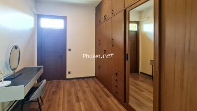 Spacious bedroom with wooden flooring, built-in wardrobes, and a vanity area.